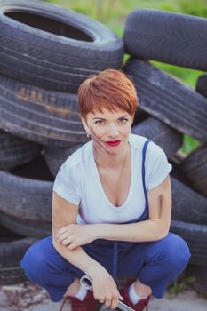 attractive woman mechanic in overalls holding wrench.