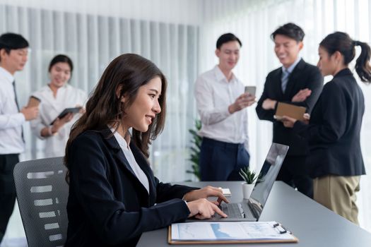 Focus portrait of female manger, businesswoman in the harmony meeting room with blurred of colleagues working together, analyzing financial paper report and dashboard data in background.