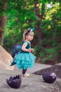 adorable baby in a dragon costume that has just hatched from an egg.