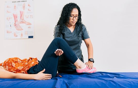Worker in modern physiotherapy assisting female patient, Professional physiotherapist assisting patient in leg rehabilitation, Modern leg rehabilitation physiotherapy