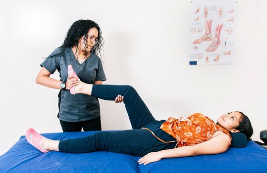 Physiotherapist assisting young patient in rehabilitation center. Modern leg rehabilitation physiotherapy. Modern physiotherapy professional assisting female patient.