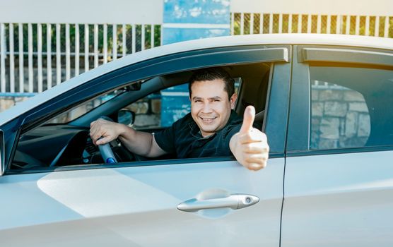 Satisfied driver man showing thumb up. Young driver man in the car showing thumb up. Happy driver giving a thumbs up on the road. safe driving concept