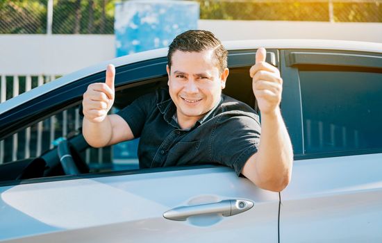 Happy driver giving a thumbs up on the road. safe driving concept. Satisfied driver man showing thumb up. Young driver man in the car showing thumb up