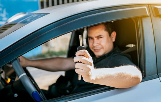 Driver in his car showing the keys out the window. Happy man showing his new car keys, Person in his vehicle showing his car keys, Satisfied car buyer concept