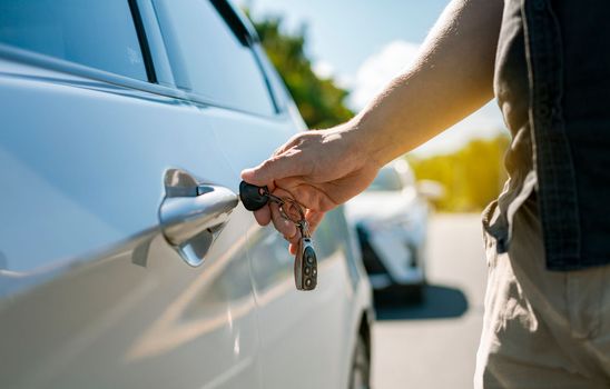 Vehicle owner opening the door with the keys. Hands with keys opening the car door. Close-up of hands opening the car door with the key