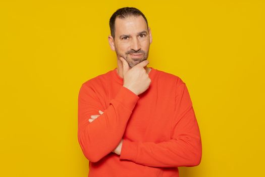 Problem solution. Bearded Hispanic man in a red jumper gets rid of a problem, and. he looks up, makes up an idea. Isolated on yellow background