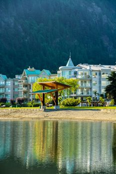 Resort buildings at waterfront on mounting forest background.