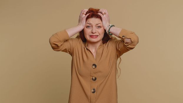 Young redhead woman feeling hopelessness loneliness, nervous breakdown, loses becoming surprised by lottery results, bad fortune, loss, unlucky news. Caucasian girl isolated on studio beige background