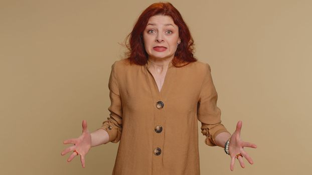 Woman in blouse screams yell from stress tension problems feels horror hopelessness fear panic surprise shock expresses gestures rage. Young pretty redhead girl isolated on beige studio background