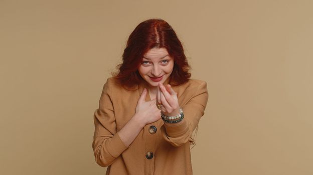 Give me money, please. Woman rubbing fingers show cash gesture, demands to pay back the debt, take loan, do shopping, begging, investment, reward. Young ginger girl isolated on beige studio background