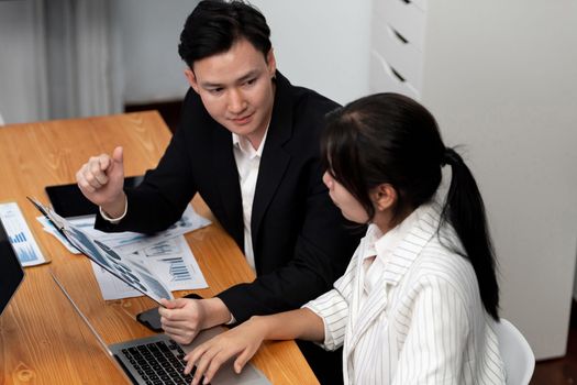 Harmony in office concept as business people analyzing dashboard paper together in workplace. Young colleagues give ideas at manager desk for discussion or strategy planning about project.