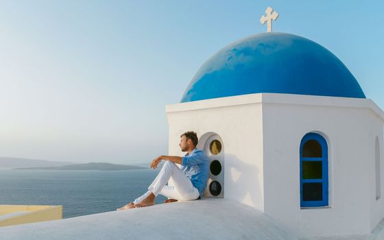 young men at Oia Santorini Greece on a sunny day during summer with whitewashed homes and churches, Greek Island Aegean Cyclades