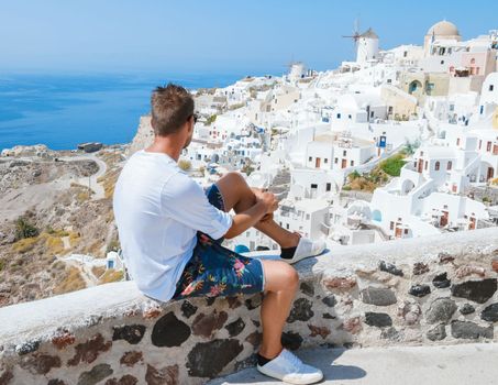 young men at Oia Santorini Greece on a sunny day during summer with whitewashed homes and churches, Greek Island Aegean Cyclades
