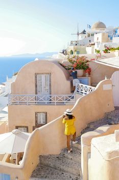 Asian women visit Oia Santorini Greece on a sunny day during summer with whitewashed homes and churches, Greek Island Aegean Cyclades