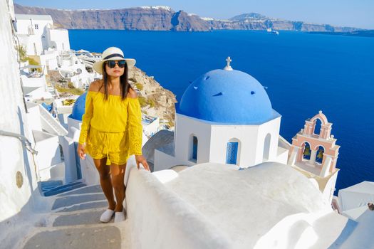 Asian women visit Oia Santorini Greece on a sunny day during summer with whitewashed homes and churches, Greek Island Aegean Cyclades