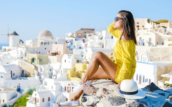 Asian woman visit Oia Santorini Greece on a sunny day during summer with whitewashed homes and churches, Greek Island Aegean Cyclades