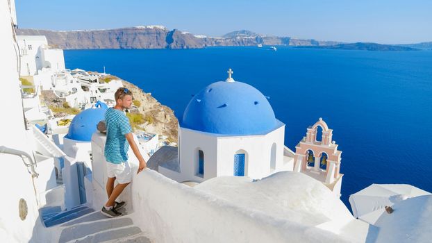 Young men tourists visit Oia Santorini Greece on a sunny day during summer with whitewashed homes and churches, Greek Island Aegean Cyclades