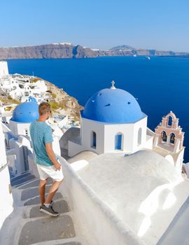 Young men tourists visit Oia Santorini Greece on a sunny day during summer with whitewashed homes and churches, Greek Island Aegean Cyclades