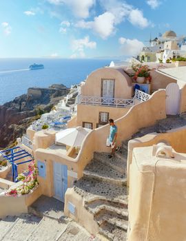 Young men tourists visit Oia Santorini Greece on a sunny day during summer with whitewashed homes and churches, Greek Island Aegean Cyclades