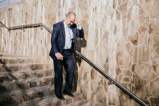 Portrait of a senior professional man in a suit with various problems. A middle-aged businessman with a briefcase descends the stairs.