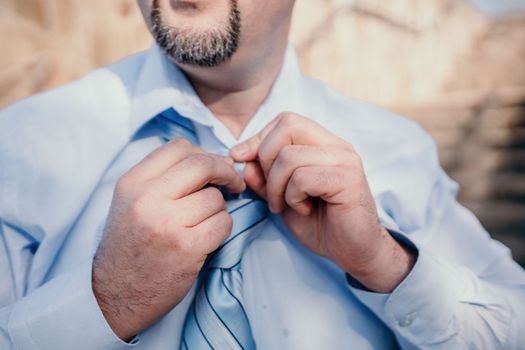 Close up of Man Adjusting Tie of Suit. Businessman in white shirt straightens his tie, close-up.