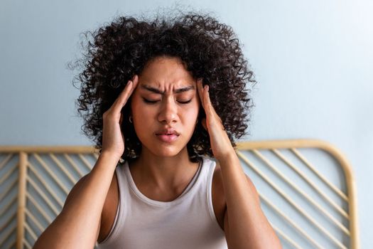 Young African American woman touching temples and frowning having headache at home. Wellbeing concept.