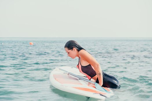Sea woman sup. Silhouette of happy young woman in pink bikini, surfing on SUP board, confident paddling through water surface. Idyllic sunset. Active lifestyle at sea or river. Slow motion