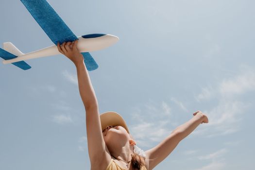 Kid playing with toy airplane. Children dream of travel by plane. Happy child girl has fun in summer vacation by sea and mountains. Outdoors activities at background of blue sky. Lifestyle moment