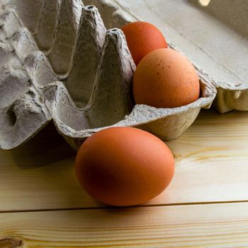 Eggs in a cardboard box, square photo. Eggs in a cardboard box on a wooden table.