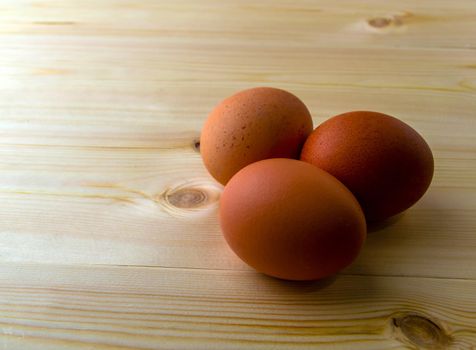 Three eggs on a wooden table. Three eggs on a wooden table close-up.