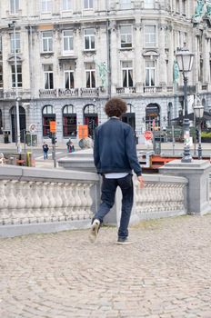 Happy optimistic African American man with curly thick black hair walks in city, Intentional motion blur, Antwerp, Belgium, 12 July 2019. High quality photo
