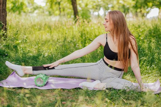 A attractive young lady stretches her body in preparation for a mid morning workout at an open field.