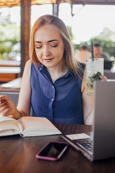 Beautiful woman with short hair sitting at the terrace on a sunny day working from home using laptop