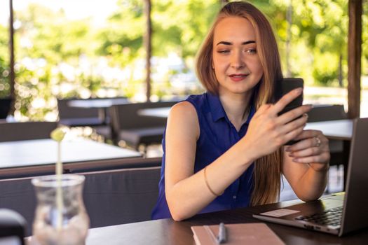 a girl sits on a summer terrace and works at a laptop. freelance. selfeducation. the concept of remote learning and outdoor work