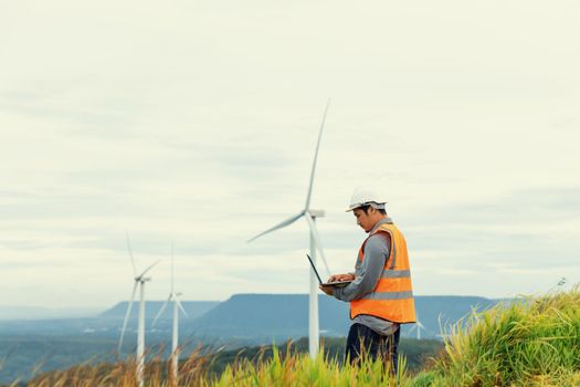 Engineer working on a wind farm atop a hill or mountain in the rural. Progressive ideal for the future production of renewable, sustainable energy. Energy generation from wind turbine.