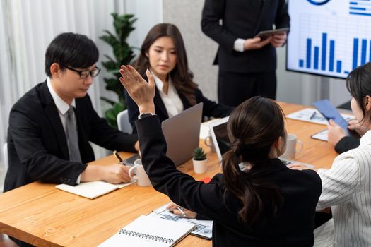 Harmony group businesspeople in meeting room during presentation with dashboard BI financial data displayed on screen, motivated employee raising hand asking question as productive teamwork concept.