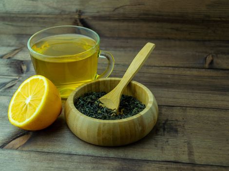 Green tea in a glass mug, lemon and dry tea. Green tea in a glass mug, lemon and dry tea in a cup on a wooden table.