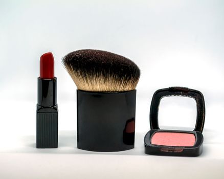 Red lipstick, blush and cosmetic brush. Red lipstick, pink blush and cosmetic brush on a white background.