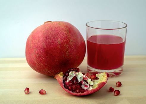 Pomegranate and pomegranate juice, photo. Photo of pomegranate and pomegranate juice in a glass on a wooden table.