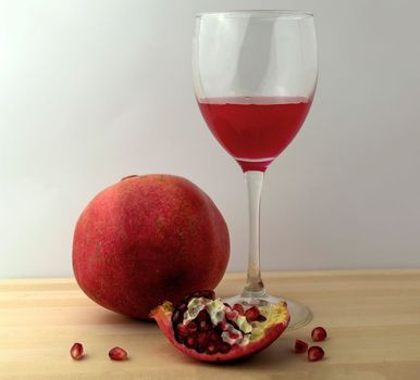 Pomegranate and pomegranate juice in a glass, photo. Photo of pomegranate and pomegranate juice in a glass on a wooden board.
