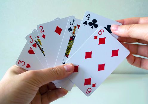 Playing cards. The left hand of the woman holds playing cards, the right hand takes out the card.