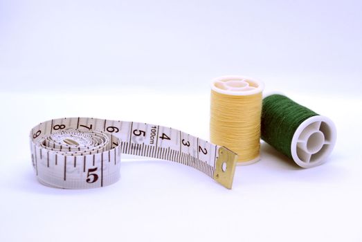 Threads and sewing ruler. In the photo, the threads are yellow and green and a sewing meter.