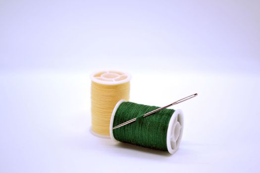 Threads and needle. In the photo, the threads are yellow and green and a needle.