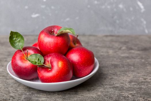 juicy red apples in a bowl or plate on the table top view. Copy space.