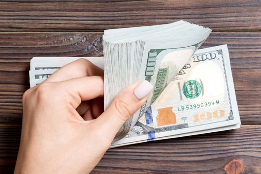 Top view of female hands counting money. One hundred dollar banknotes on colorful background. Business concept.