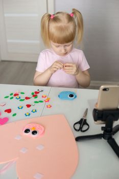 A blogger girl makes a felt craft for Valentine's Day in the shape of a heart. The concept of children's creativity and handmade.