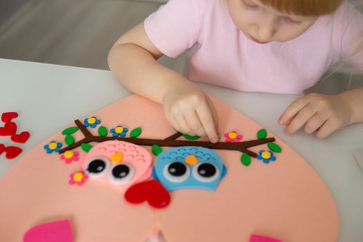 A blogger girl makes a felt craft for Valentine's Day in the shape of a heart. The concept of children's creativity and handmade