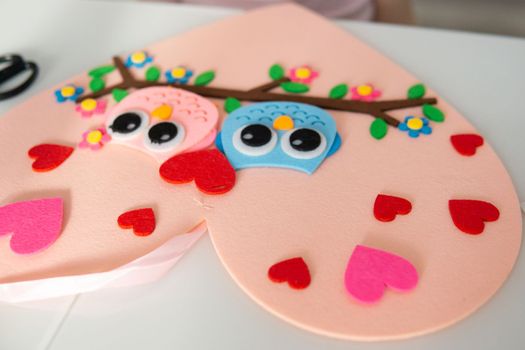 A blogger girl makes a felt craft for Valentine's Day in the shape of a heart. The concept of children's creativity and handmade.