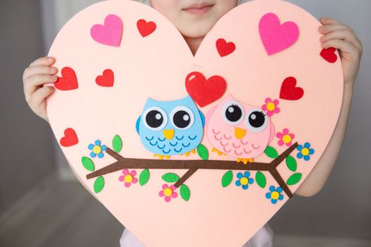 A blogger girl makes a felt craft for Valentine's Day in the shape of a heart. The concept of children's creativity and handmade