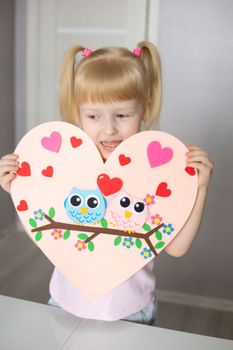 A blogger girl makes a felt craft for Valentine's Day in the shape of a heart. The concept of children's creativity and handmade